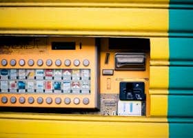 Detailed view of a vibrant yellow and green cigarette vending machine interface.